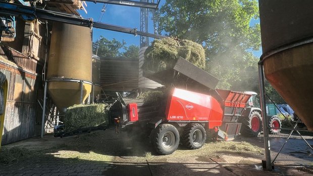 Eine Ballenpresse presst loses Heu aus dem Heustock zu Ballen.