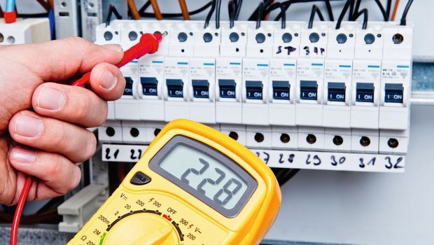 Ein Multimeter wird bei einem Sicherungskasten benutzt, um die Stromspannung zu messen.