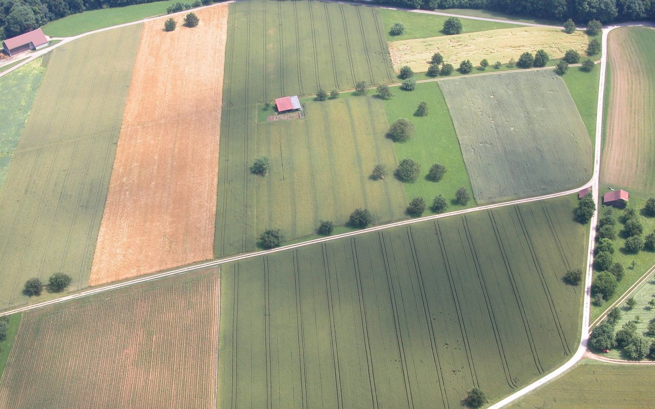 Eine Luftaufnahme von Schweizer Kulturland, mit vielen kleinen Feldern.