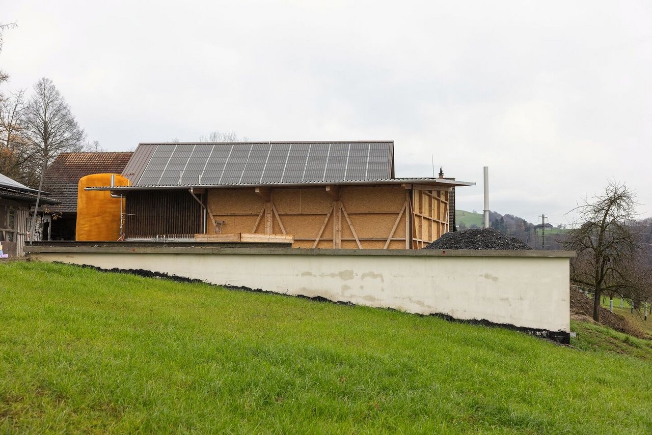 Unscheinbare Energiewirtschaft: Der Fermenter, das Herzstück der Biogasanlage im Vordergrund fällt auf dem Hof kaum auf, dahinter die grosse Photovoltaik-Anlage und daneben der grosse gelbe Wärmespeicher.