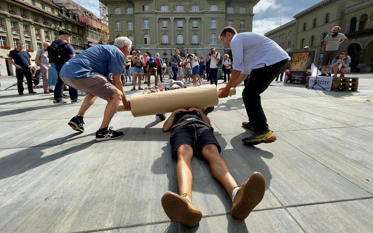 Bauern und Bäuerinnen werden von einer symbolischen «Walze der Grossverteiler» überrollt