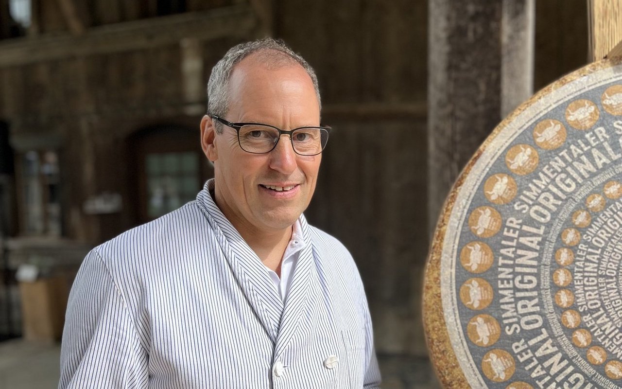 Jakob Siegenthaler steht mit angeschnittenem Käse vor der Etikette des "Simmentaler Originals".