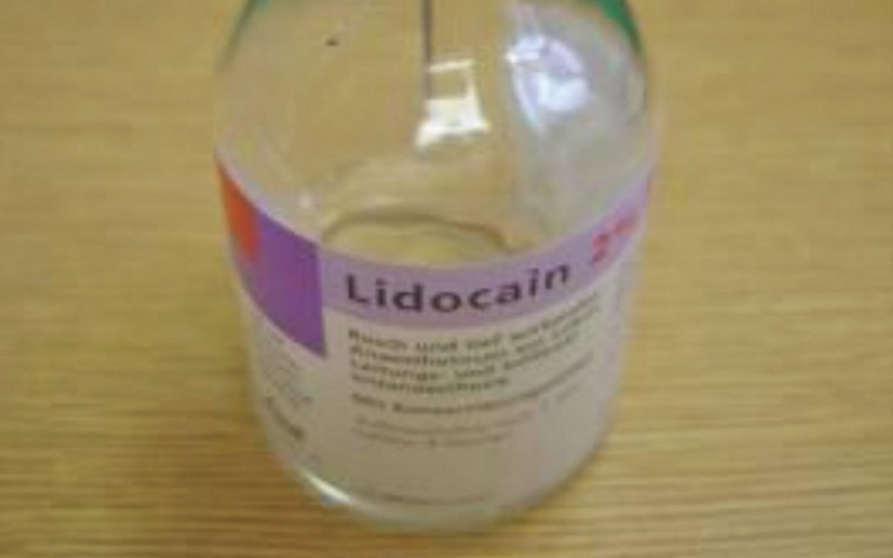 Eine Flasche des Lokalanästhetikums Lidocain, in welcher eine Spritzenspitze im Gummi steckt.