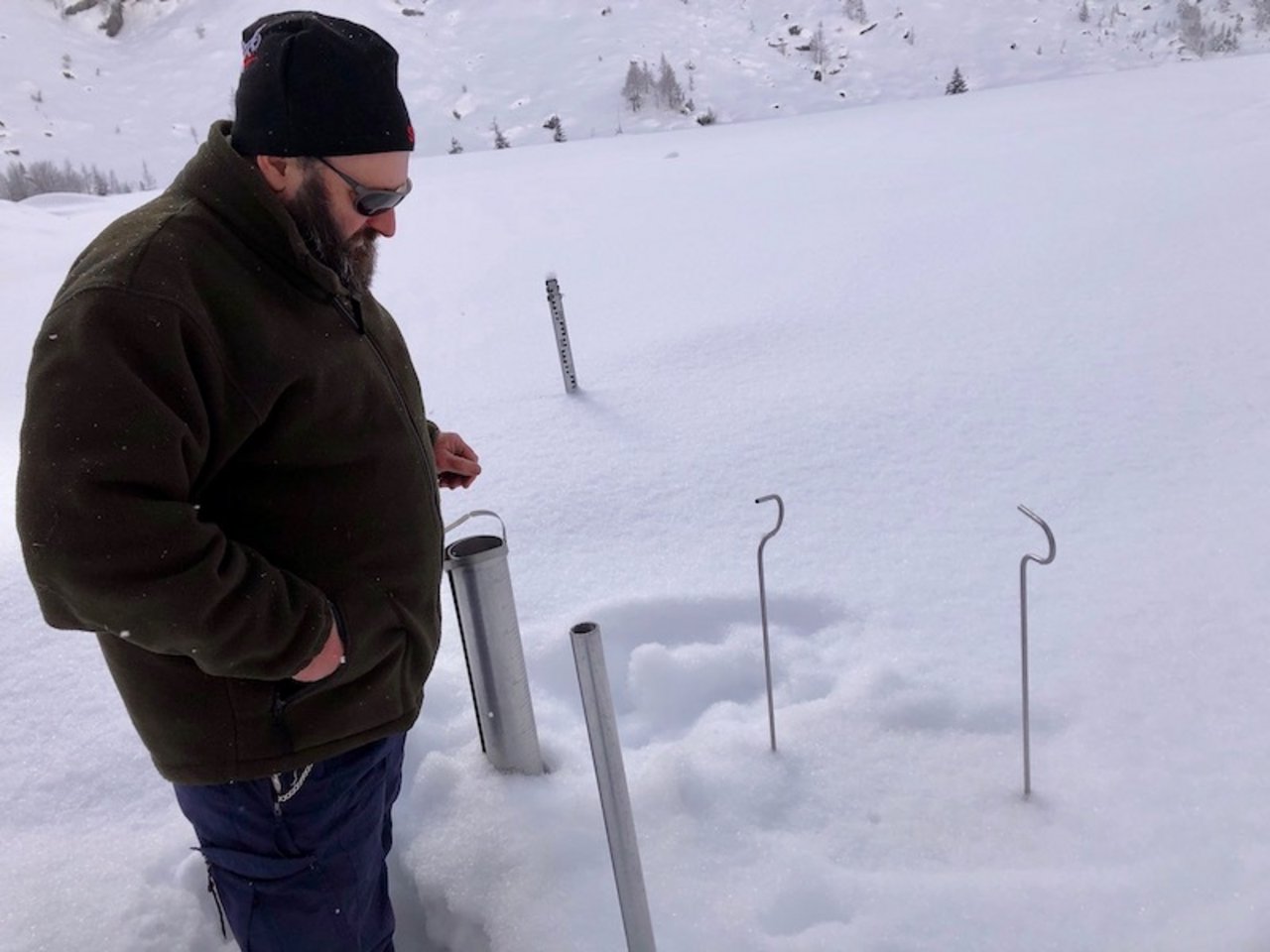Christof Mattli bei seiner Arbeit als Lawinenbeobachter: im Hintergrund Messstange für die Messung Schneemenge gesamt. Die dünnen Metallstäbe gehören zum eingeschneiten Tablar, mit dem er die Neuschneemenge ermittelt.