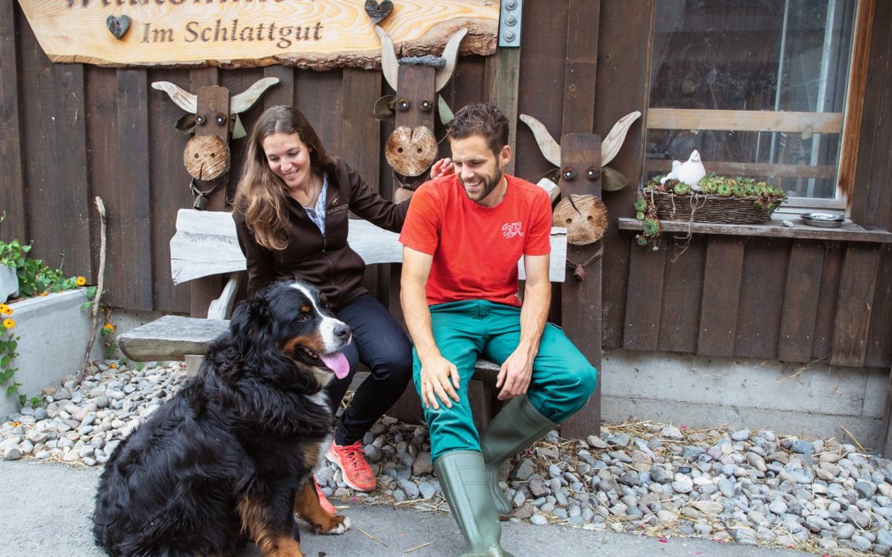 Ruhige Momente auf der Bank vor der Event-Scheune sind bei Caroline Wyss und Domenik Ledergerber rar – auch Hofhund Maiko will dabei sein. Bild: Gian Vaitl