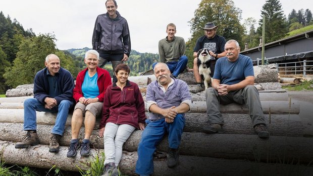 Tierhaltergemeinschaft Gruppenbild der drei Familien, wie sie auf Holzstämmen sitzen.