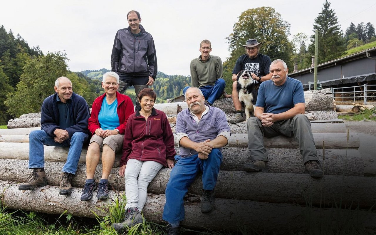 Gruppenbild der drei Familien, wie sie auf Holzstämmen sitzen.