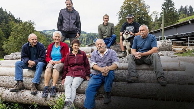 Tierhaltergemeinschaft Gruppenbild der drei Familien, wie sie auf Holzstämmen sitzen.