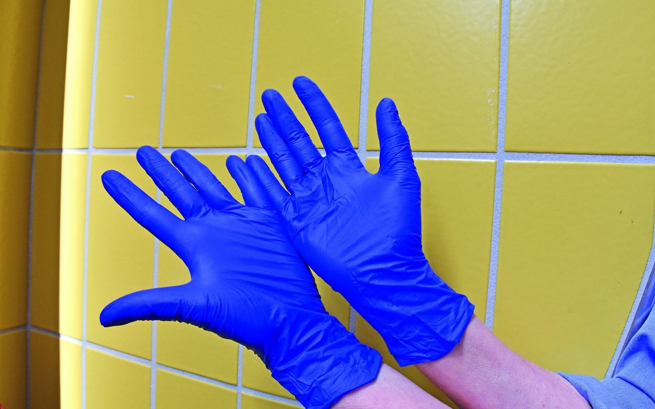 Zwei Hände mit blauen Hygiene-Handschuhen