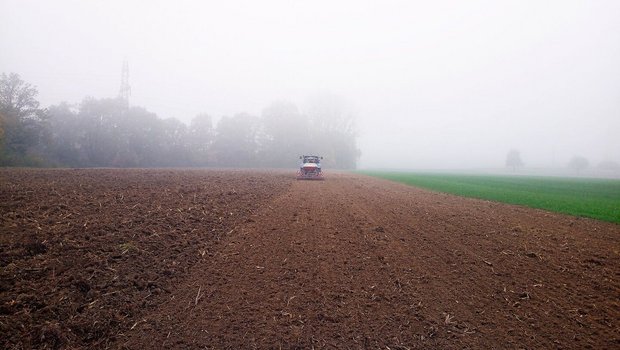 Traktor fährt mit der Sämaschine über das Feld.