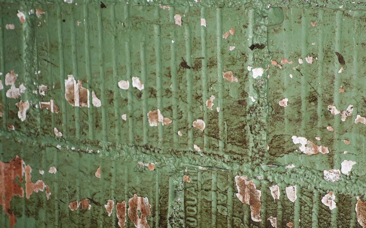 Eine grüne Stallwand, von der die Farbe abblättert.