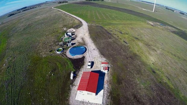 Wohnhaus, Container und Wasserreservoir sowie im Hintergrund die Linien mit den ersten Pekanbäumen. 