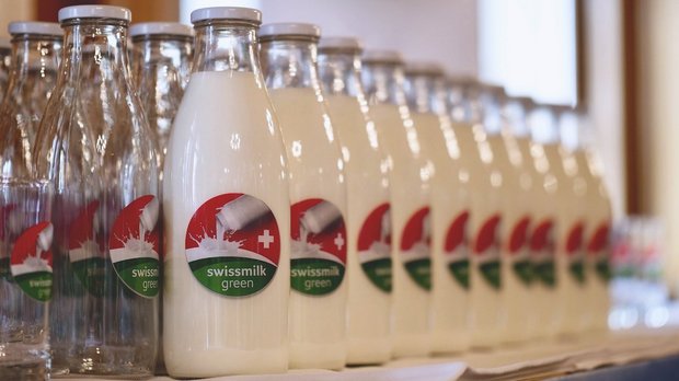 Eine Reihe Milchflaschen mit der Marke «swissmilk green».