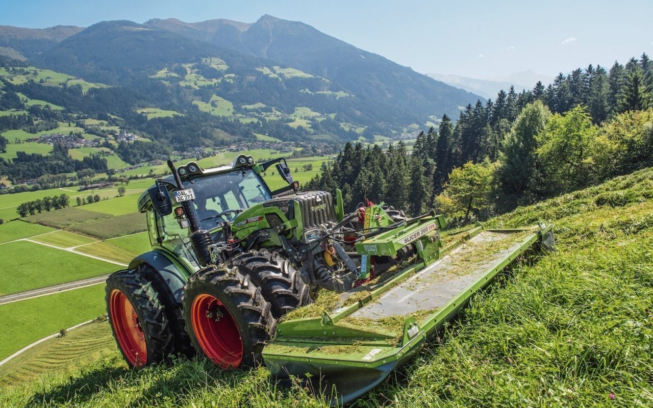 Der Fendt 211 Vario Traktor bei Mähen im Berggebiet.