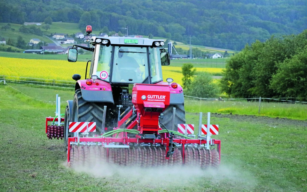 Traktor mit angehängter Sämaschine macht eine Übersaat auf einer Naturweide.