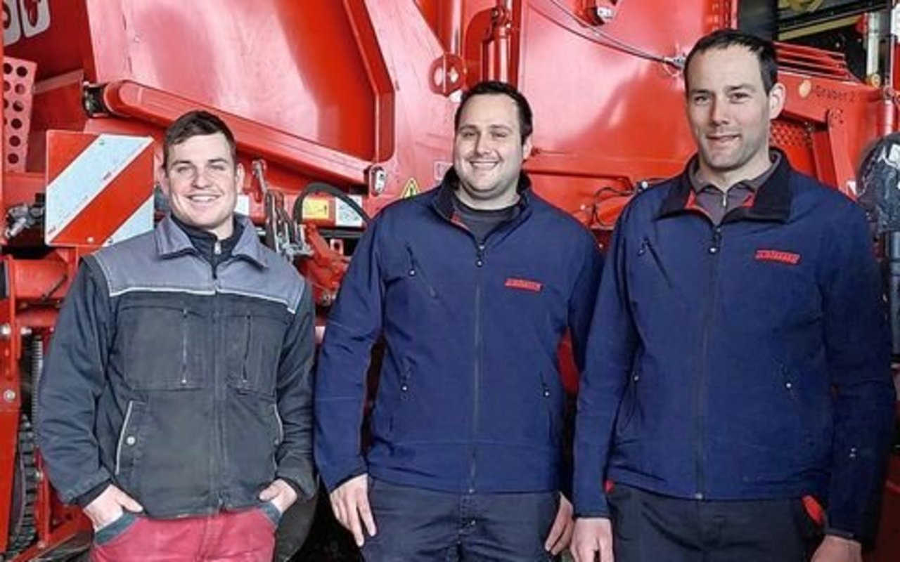 Christian Mollet, Stefan Wyss und Daniel Wyss stehen vor einem roten Kartoffelernter.