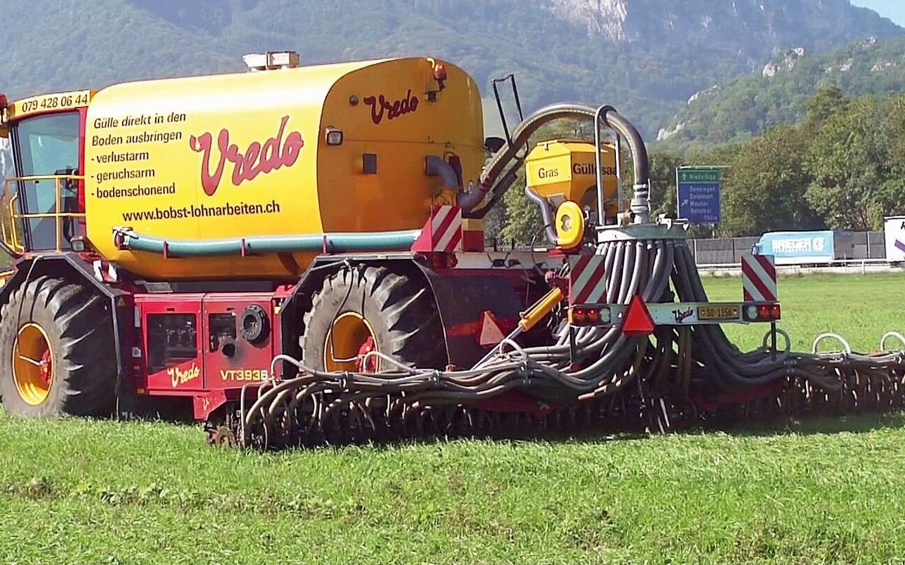 Ein selbstfahrendes Güllefass hat ein Sägerät aufgebaut und fährt damit über das Feld.