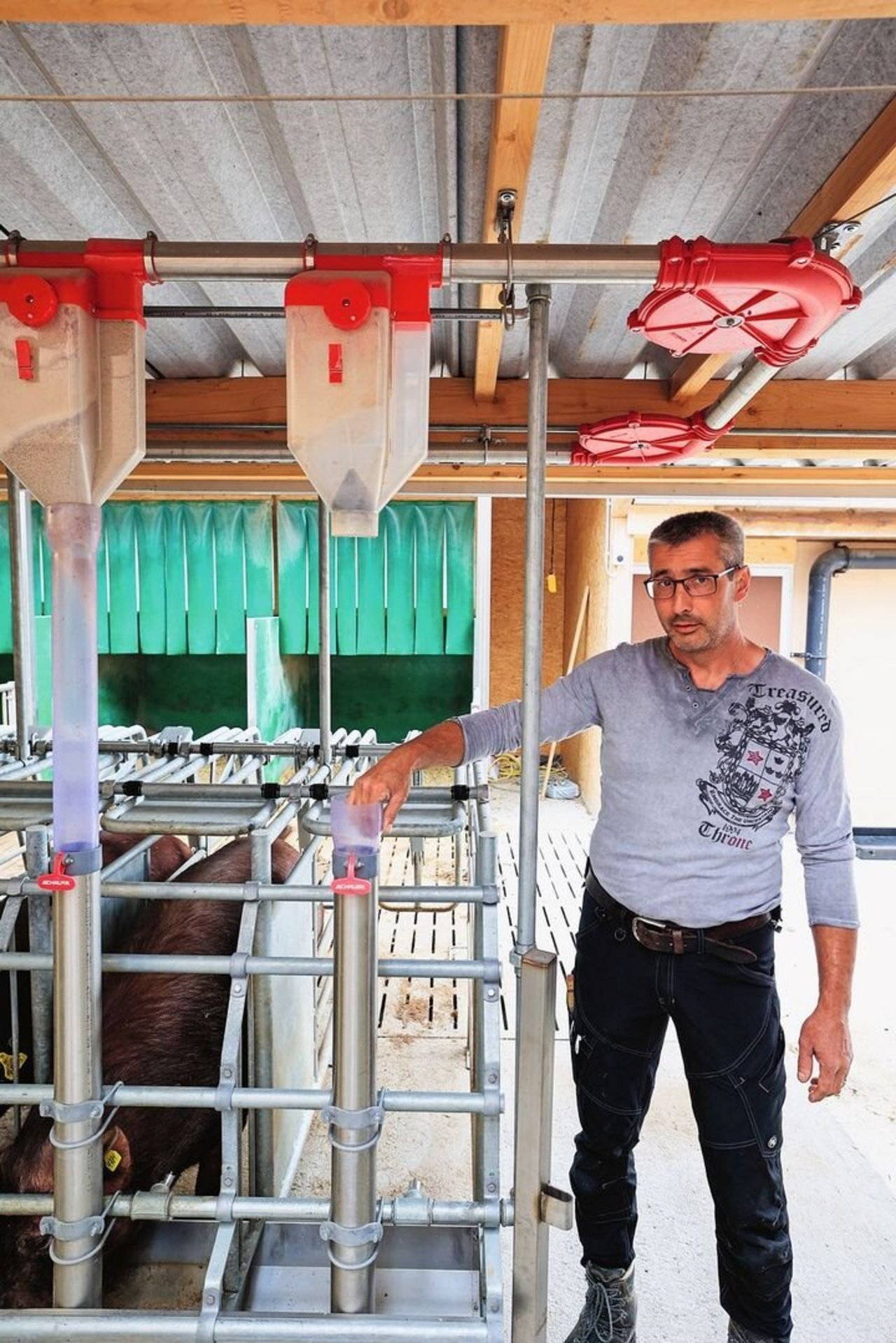 Ruedi Huber steht neben dem Fressstand seiner Schweine und zeigt auf die durchsichtigen Röhren, die ausserdem praktisch auseinander genommen werden können.