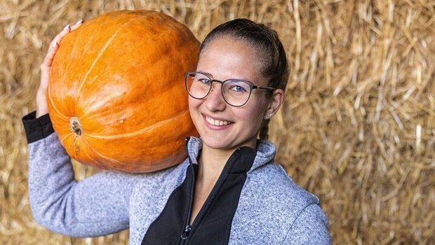 Faye Kleiner schultert einen Kürbis.