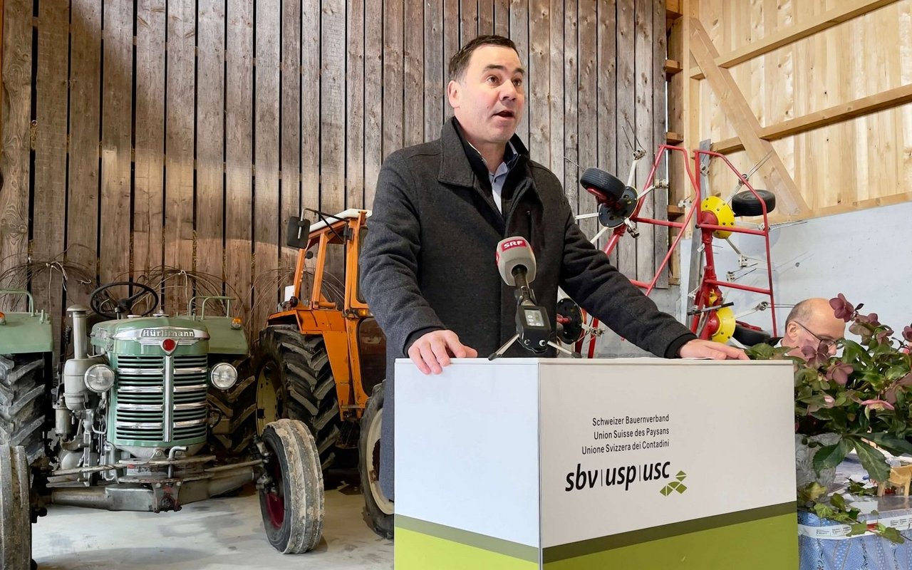 SBV-Direktor Martin Rufer am Rednerpult, im Hintergrund ein alter Hürlimann-Traktor.