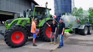 Flavio Näf (links), Florian Abt (Mitte) und Marco Landis (rechts) von der Swiss Future Farm stehen vor dem Traktor, an dem ein Güllefass angehängt ist.