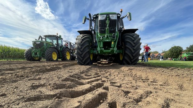 Zwei John Deere-Traktoren mit Traxion-Reifen, im Vodergrund der Prodilabdruck im Acker.