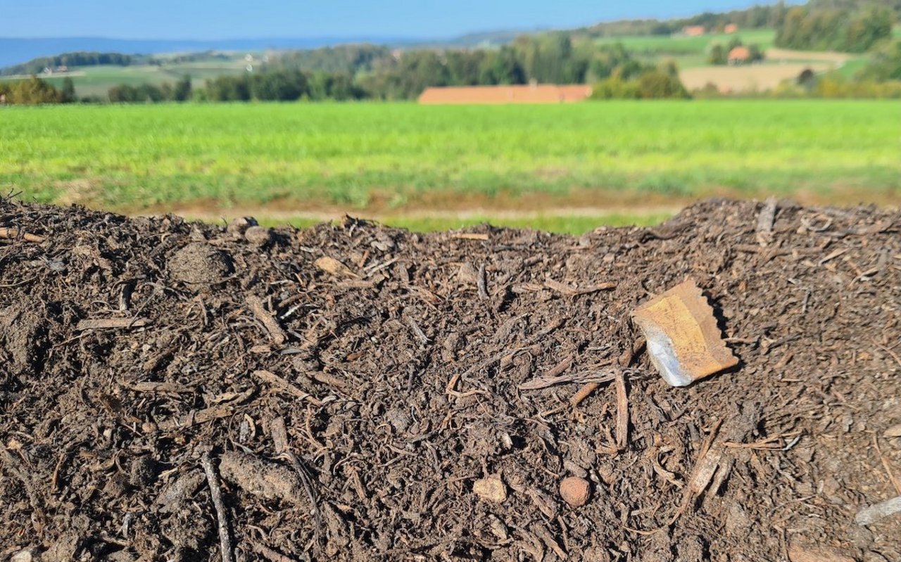 An einer Kompostmiete am Feldrand sind diverse Verpackungen und Fitzelchen von Plastik zu sehen.