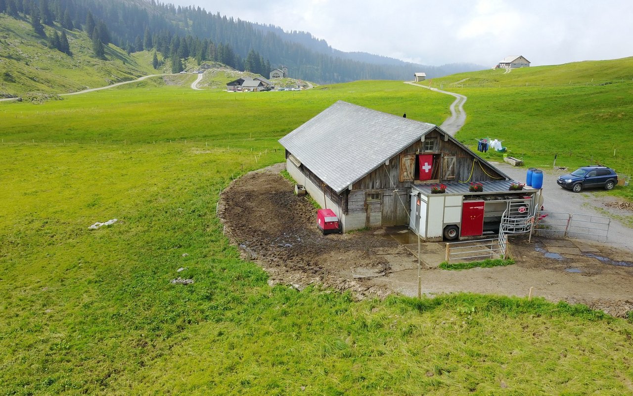 Der Melkroboter auf der Alp Pragel mit Milchtank und den Kraftfutterfässern auf dem Dach des Melkroboters.